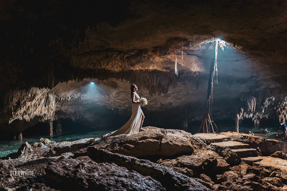 Bride standing in the center of a cave cenote at Cenote Tak Be Ha, surrounded by rock formations in Riviera Maya