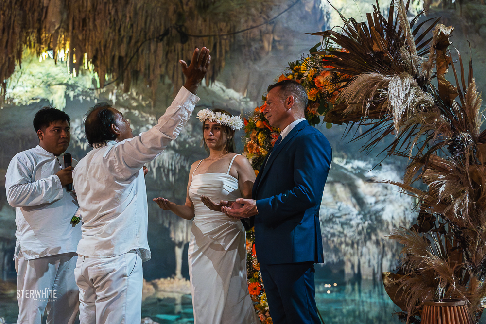 Mayan shaman giving a blessing to the couple during a traditional ceremony inside a cenote