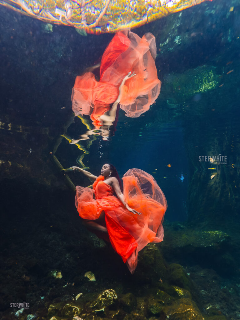 Underwater birthday portrait in a cenote with a orange flowing dress